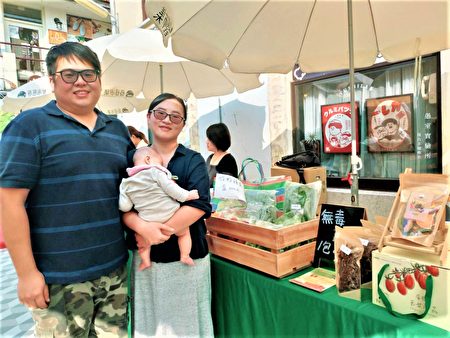 經營苗栗「饗甜蔬果農場」的年輕夫婦，抱著5個月大的小女嬰參加展示會。（黃玉燕／大紀元）
