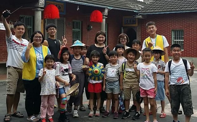 (王元弘(左1)、許雅筑(左2)、陳祈佑(左3，黑色衣服)及魏智瀚同學(右，黃色背心)帶領兒童營隊後與小朋友合照。圖由 教育部 提供)