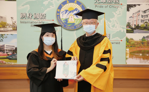 畢業生代表穆品齊(左)致贈畢業紀念冊予艾群校長