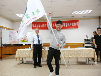  NCYU President Chyung Ay (middle) presented a flag to Dong Yan-Zhen (middle), who represented the Agronomy Volunteer Team.