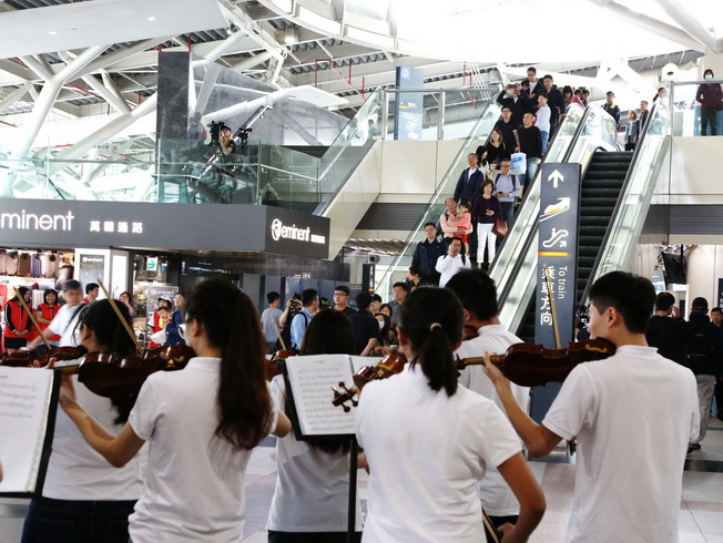 The passengers walking out of the exit were pleasantly surprised by the flash mob event.