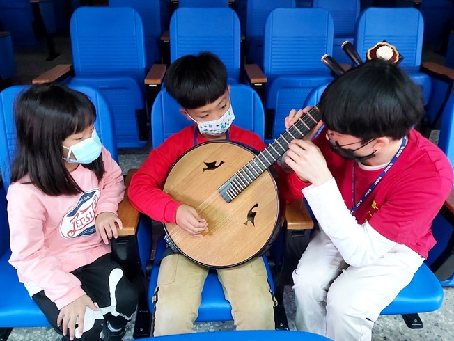 嘉大國樂團引導國小學童體驗中國傳統樂器「中阮」。(照片由課活組提供)