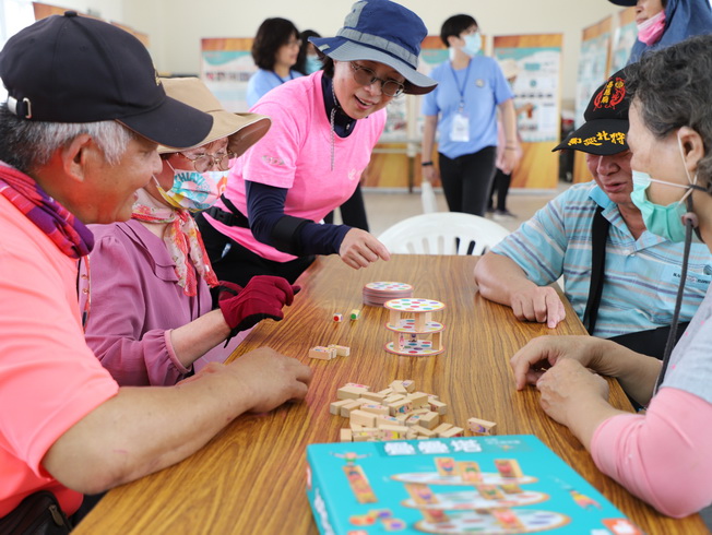 嘉大體育與健康休閒學系丁文琴老師教導社區長輩玩桌遊。